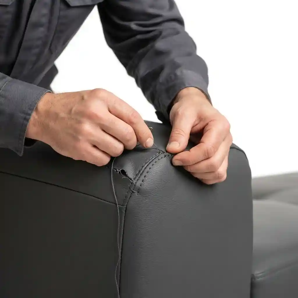 Upholsterer fitting faux leather on a sofa armrest