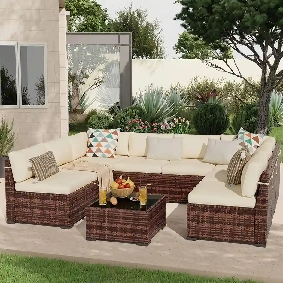 L-shaped brown wicker garden sectional with cream cushions and patterned pillows around a matching coffee table